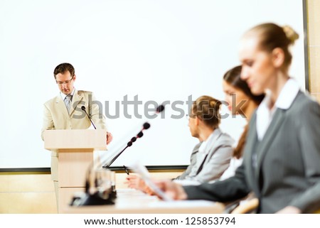 businessmen talking at the conference, sitting at the table, on the table microphones and documemts