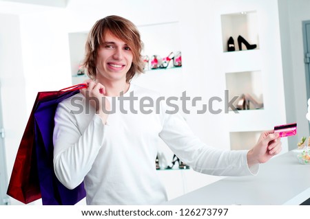 Young man at shopping mall checkout counter paying through credit card