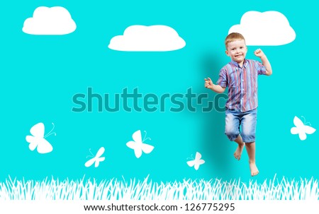 boy jumping on the background of painted wall with grass, clouds and butterfly collage of a happy childhood, place for text