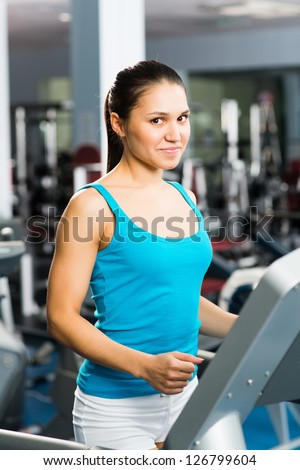 attractive young woman runs on a treadmill, is engaged in fitness sport club