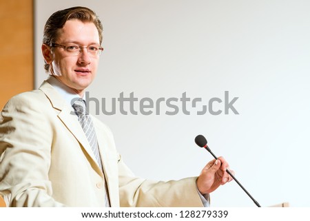 Portrait of a business man holding a microphone and looking at the camera