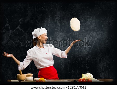 Asian female chef tosses a piece of dough, creative cooking