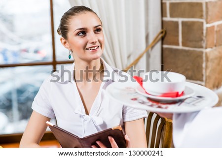 waiter brings a dish for a nice woman at the restaurant, she looks at him and smiles