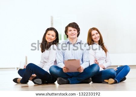 portrait of a group of young people sitting on the floor, man and two attractive women