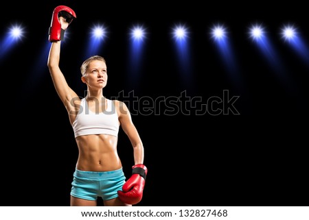 female boxer is in the rays of lights, raised a hand in a glove