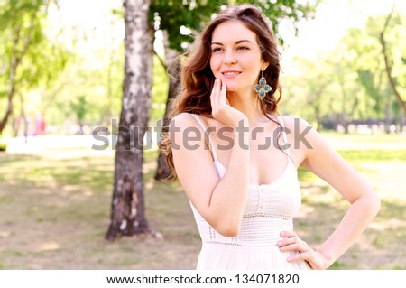 Portrait of an attractive woman in the park, looking ahead and smiling