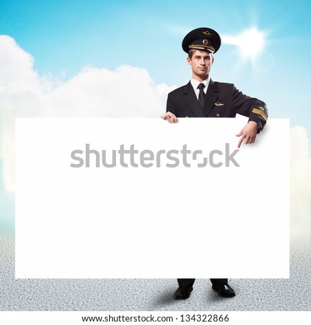 pilot in the form of holding an empty billboard on the background of sky with clouds, place for text