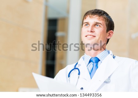 Portrait of a doctor holding papers in hand, office space
