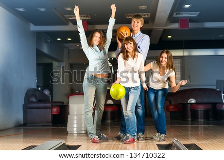 Group of young friends playing bowling, spending time with friends