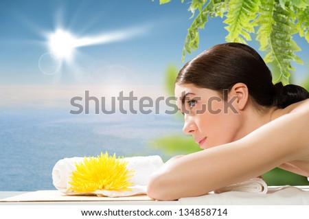 beautiful spa woman lying on the couch, in front of her flower and rolled towel