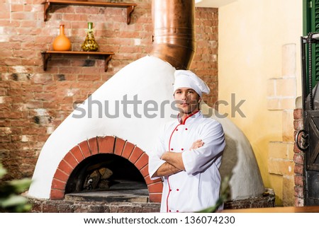 portrait of a cook in the kitchen near the wood-burning oven for pizzas, traditional cuisine