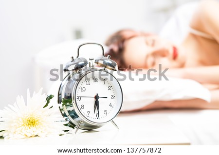 close-up alarm clock next to the sleeping people