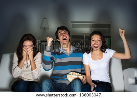 group of young people watching TV on the couch, sports fans