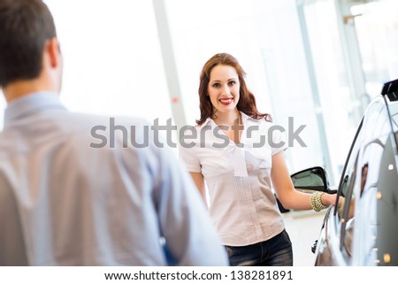 cute woman chooses a new car in the lounge car sales