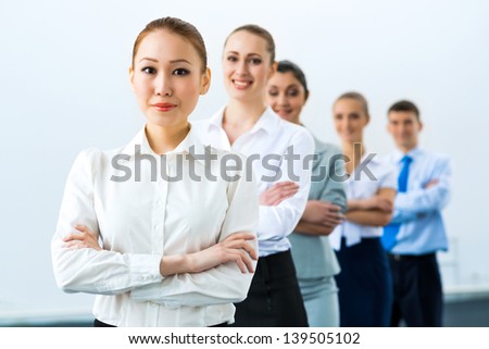 group of business people standing in a row, smiling and crossing his arms