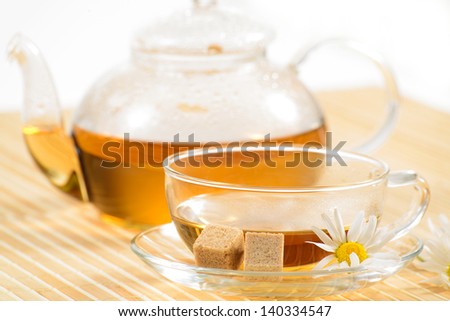 A teacup and a teapot with herbal chamomile tea