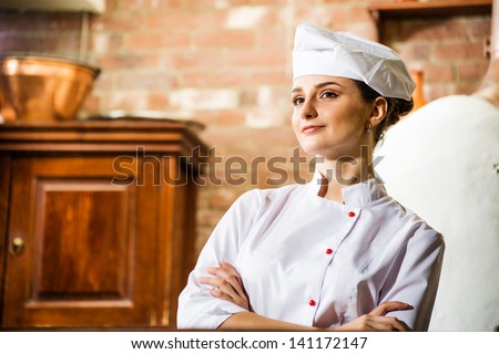 portrait of a cook, is on the traditional kitchen, crossed her arms