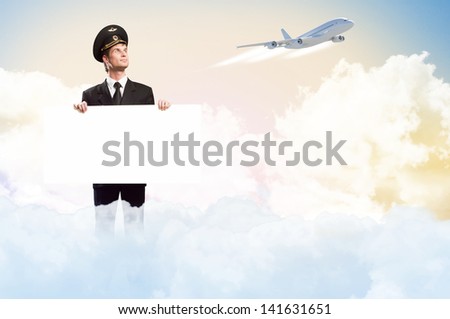 pilot in the form of holding an empty billboard on the background of sky and flying plane, place for text