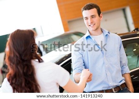 man shaking hands with car salesman, buying a new car