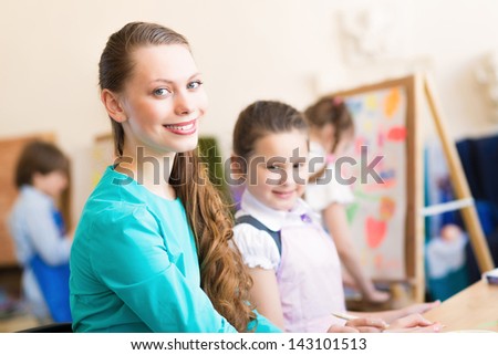 children with the teacher engaged in painting at an art school