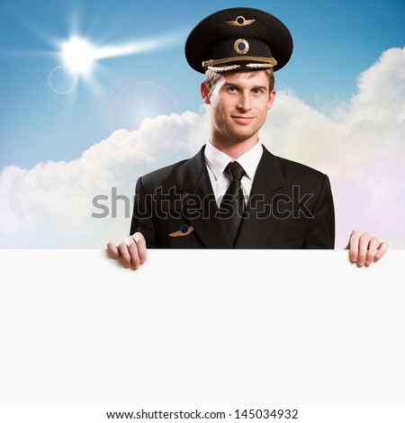 pilot in the form of holding an empty billboard on the background of sky with clouds, place for text