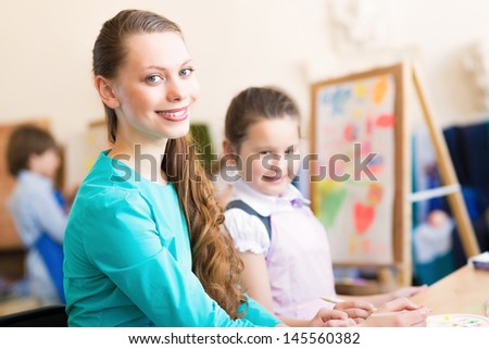 children draw with the teacher in the classroom drawing