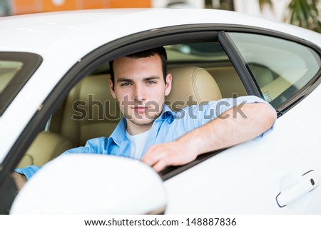 portrait of a man sitting in a sports car in the showroom, make expensive purchases