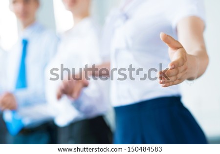 invitation to the team, business woman holds out her hand, her face a number of young businessmen