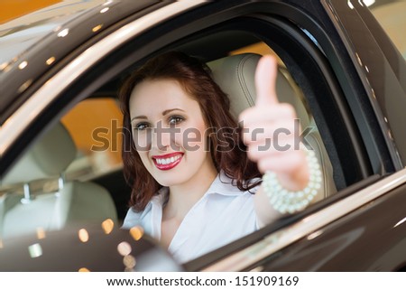 woman sitting in a new car, showing thumb up, focus on the face