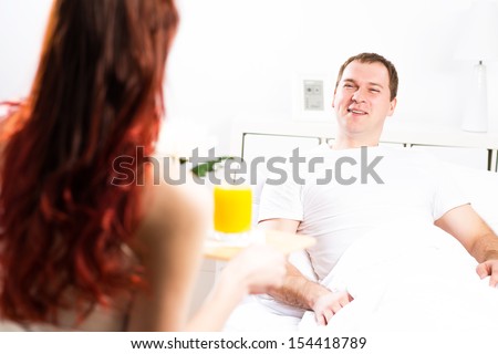 woman brought her boyfriend breakfast in bed, holding a tray of juice and breakfast