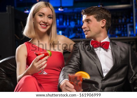 couple in a nightclub on the couch with a drink, have fun