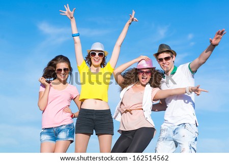 Group of young people having fun on a blue summer sky