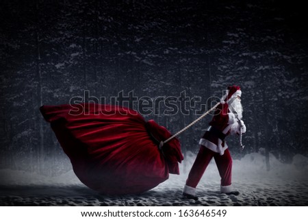 Santa Claus in a night winter forest pulling a huge bag of gifts