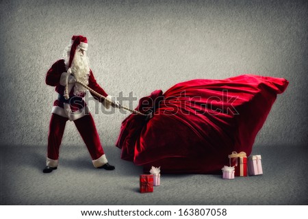 Santa Claus pulls a huge bag of gifts lying around boxes with gifts