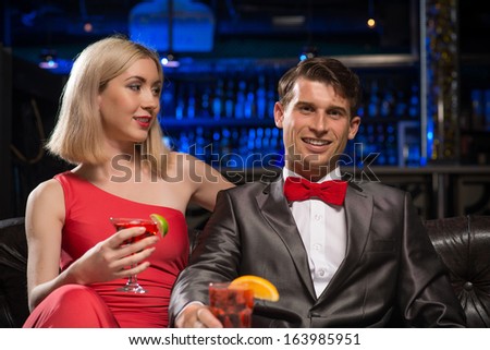 couple in a nightclub on the couch with a drink, have fun