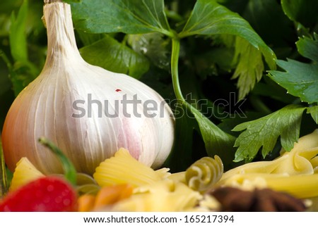 Close-up of garlic and basil leaves, pasta around