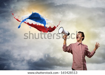 Portrait of a young man shouting using megaphone, of the horn fly, splashes of paint