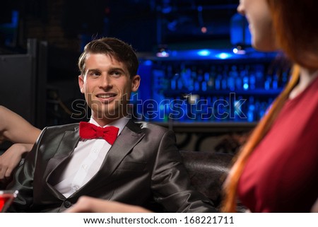 portrait of a man in a nightclub, sitting on the couch and talking with the woman, a date at a nightclub.