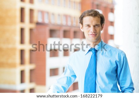successful young businessman smiling, standing on the balcony