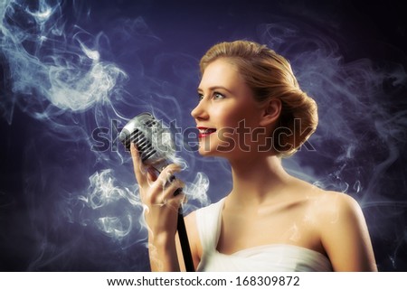 beautiful blonde woman singer with a microphone, eyes opened, around smoke
