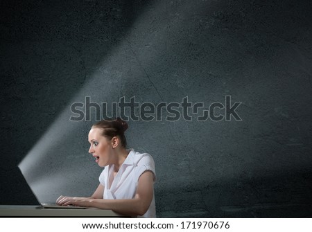 young attractive woman holding a cell phone in a dark room at her glow from the monitor