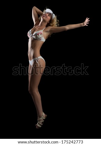 young woman in bikini and hat dancing, isolated on black background
