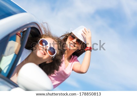 young attractive woman in sunglasses got out of the car window and laugh