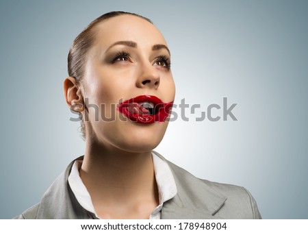 young woman with vivid red mouth, smiling and licking mouth