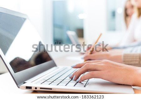 close-up of female hands on the laptop keyboard, students listen to the teacher at the University of