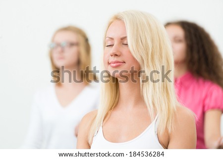 portrait of an attractive young woman, meditating with closed eyes, group meditation