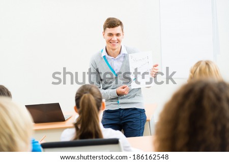 young teacher man talking with students in the classroom