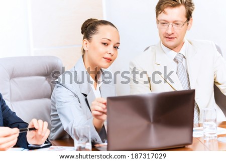 Business people talking, sitting at the table, watching the presentation on a laptop