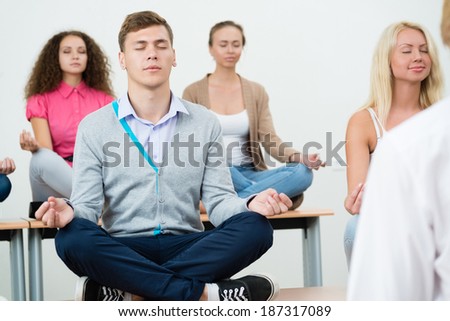 group of young people meditating in office at desk, group meditation