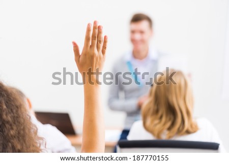 image of a female hand raised in university classroom